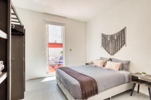 ein weißes Schlafzimmer mit einem Bett und einem Fenster in der Unterkunft Casa Lumo in Roma Norte by Tasman in Mexiko-Stadt