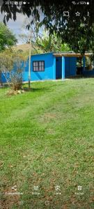 um edifício azul num quintal com um campo de relva em Casa e camping Reinaldo e Julia recanto das árvores em Itamonte