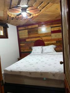 a bedroom with a bed with a wooden wall at Spirit Mountain/El Espíritu de la Montaña in La Unión