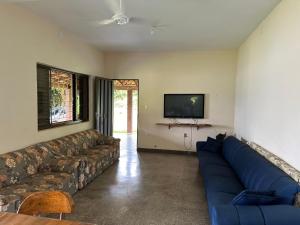 a living room with a blue couch and a tv at RANCHO SAPUCAÍ in Passos