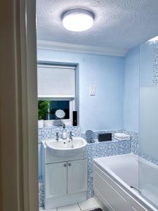 Baño azul con lavabo, bañera y lavabo en Immaculate 2-Bed Apartment in Rochester, en Rochester