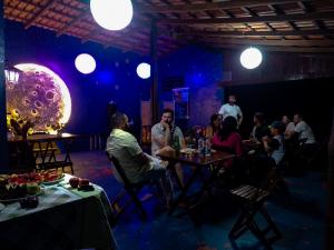 um grupo de pessoas sentadas à mesa numa sala em Pousada Estação Lunar em São Domingos