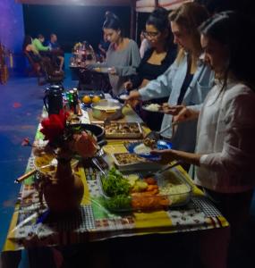 um grupo de pessoas à volta de uma mesa com comida em Pousada Estação Lunar em São Domingos