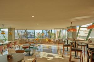 a restaurant with tables and chairs and windows at Dreams Lanzarote Playa Dorada Resort & Spa in Playa Blanca