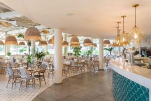 a dining room with tables and chairs and chandeliers at Alua Suites Fuerteventura - All Inclusive in Corralejo