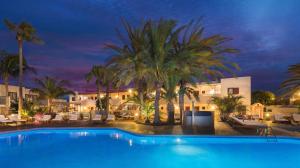 a swimming pool with palm trees and a hotel at Alua Suites Fuerteventura - All Inclusive in Corralejo