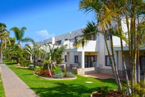 a building with palm trees in front of it at Alua Suites Fuerteventura - All Inclusive in Corralejo