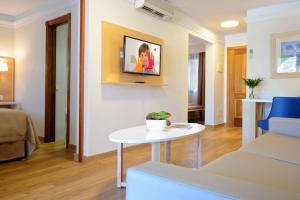 a living room with a table and a tv on a wall at Alua Suites Fuerteventura - All Inclusive in Corralejo