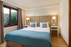 a bedroom with a large bed with blue and white pillows at Alua Suites Fuerteventura - All Inclusive in Corralejo