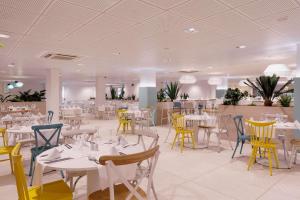 a dining room with white tables and yellow chairs at Alua Suites Fuerteventura - All Inclusive in Corralejo
