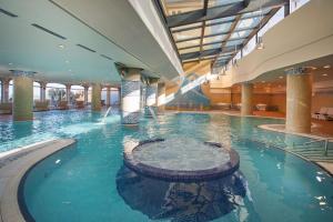 una gran piscina en un gran edificio con una fuente de agua en Secrets Bahía Real Resort & Spa Adults only, en Corralejo