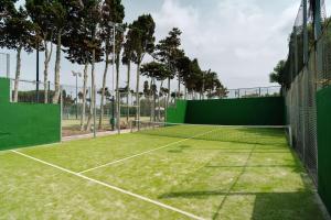 una pista de tenis con una valla verde y árboles en Alua Illa de Menorca, en S'Algar