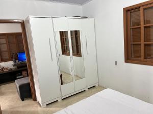 Cette chambre comprend une armoire blanche et une télévision. dans l'établissement Residencial Pôr do Sol Estrada do Palmital, Osório RS, à Osório
