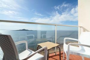 balcón con sillas, mesa y vistas al océano en AluaSun Doblemar, en La Manga del Mar Menor