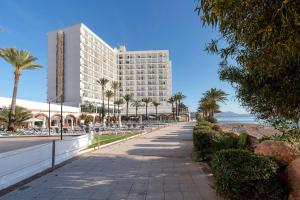 un edificio en la playa con palmeras y una acera en AluaSun Doblemar, en La Manga del Mar Menor