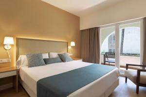 Habitación de hotel con cama grande y balcón. en AluaSoul Menorca - Adults Only en S'Algar