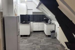 uma cozinha com armários brancos e pisos em azulejo preto em Tulsa Home - Comme à la maison em Saint-Quentin