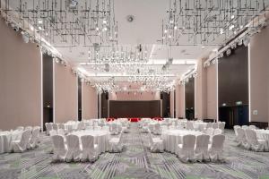 um salão de banquetes com mesas e cadeiras brancas e lustres em Holiday Inn Taiyuan Sunshine, an IHG Hotel em Taiyuan