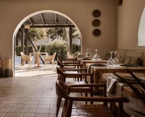 イエラペトラにあるNumo Ierapetra Beach Resort Crete, Curio Collection Hiltonのレストランのテーブルと椅子