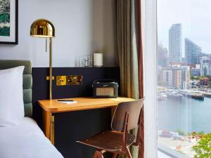 Habitación de hotel con escritorio, cama y ventana en TRIBE London Canary Wharf, en Londres