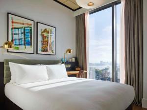- une chambre avec un grand lit et une grande fenêtre dans l'établissement TRIBE London Canary Wharf, à Londres