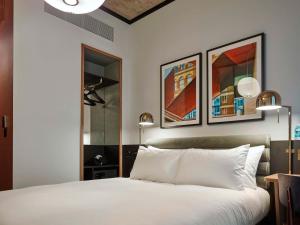 a bedroom with a white bed with two pictures on the wall at TRIBE London Canary Wharf in London