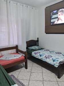 a room with two beds and a tv on the wall at Hostel do Enzo in Itanhaém