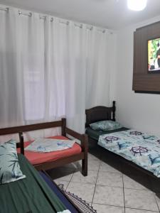 a room with two beds and a tv at Hostel do Enzo in Itanhaém