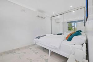 białe łóżko w białym pokoju z oknem w obiekcie Quiet Elevated Serene Home w mieście Merrylands