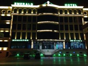 um hotel com carros estacionados em frente a ele à noite em EmeraldGold em Baku