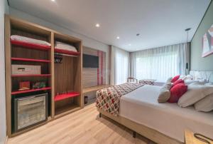 een slaapkamer met een groot bed en een televisie bij Laghetto Stilo Borges - Apto 403B in Gramado