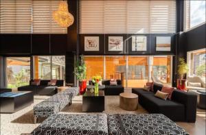 een grote woonkamer met banken, tafels en ramen bij Laghetto Stilo Borges - Apto 403B in Gramado