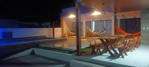 a table and chairs next to a swimming pool at night at Casa beach Japaratinga in Japaratinga