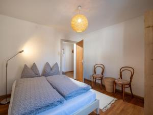 1 dormitorio con 1 cama con almohadas azules y 2 sillas en Föchlhaus am Marktgraben, en Hopfgarten im Brixental