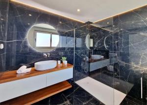 La salle de bains est pourvue d'un lavabo et d'un miroir. dans l'établissement Lê Maison Deluxe Madeira, à Ponta do Sol
