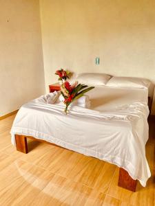 a white bed with a bouquet of flowers on it at Cabañas Iracas del Mar in Nuquí