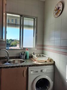 a kitchen with a washing machine and a sink at Mi bonito apartamento del Portil in El Portil