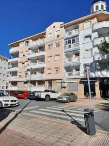 a large apartment building with cars parked in front of it at Mi bonito apartamento del Portil in El Portil