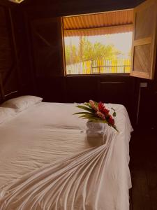 un jarrón de flores sentado en una cama con una ventana en Cabañas Iracas del Mar en Nuquí