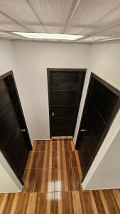- deux portes noires dans une chambre dotée de parquet dans l'établissement Family Amazon Minimalist, à Leticia