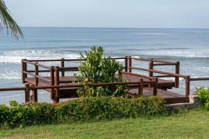 a wooden bench on the beach with the ocean at Refugio de piedra - Troncones in Troncones