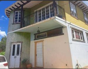 een geel en wit huis met een balkon bij Casa Temporada recanto de minas in Tiradentes