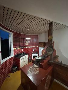 uma cozinha com paredes de azulejos vermelhos e uma cozinha com um fogão em Casa Temporada recanto de minas em Tiradentes
