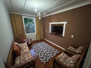 a living room with two chairs and a television at Casa Temporada recanto de minas in Tiradentes