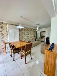 uma cozinha e sala de estar com uma mesa de madeira e cadeiras em APARTAMENTO à 100 m do mar (1 min a pé) em Bombinhas