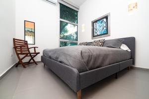 una camera da letto con un letto, una sedia e finestre di Relaxing 2 bedroom apartement in the center of tulum with private pool and terrace a Tulum