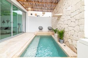 una piscina in una stanza con un muro in pietra di Relaxing 2 bedroom apartement in the center of tulum with private pool and terrace a Tulum