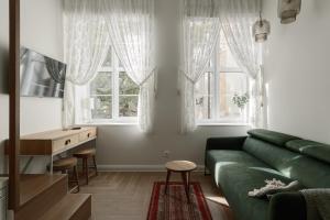 a living room with a green couch and two windows at Comfort Stay - Old Town in Klaipėda