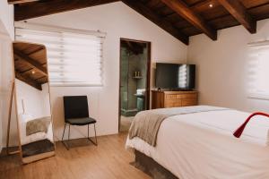 a bedroom with a bed and a chair and a television at Bärehuus Boutique Hotel in Antigua Guatemala