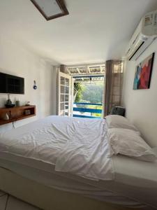 a white bed in a bedroom with a window at Casa Cristo Redentor c/piscina in Rio de Janeiro